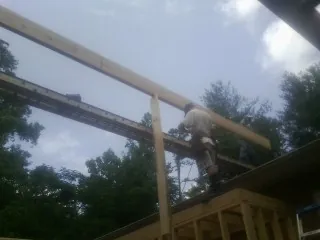 Carpenter setting a ridge beam over a new addition frame — Ice Dam Removal by Roofing Brothers in Sand Creek