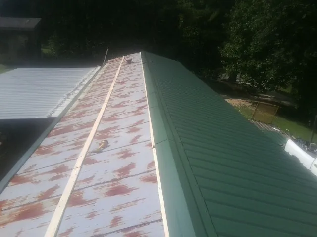 Old rusted panels beside newly installed green metal roofing — Wind Damage Roof Repair by Roofing Brothers in Sand Creek