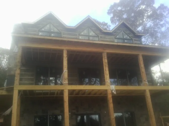 Dormers and porch framing on a large log home under construction — Roof Coating work by our crew in Sand Creek