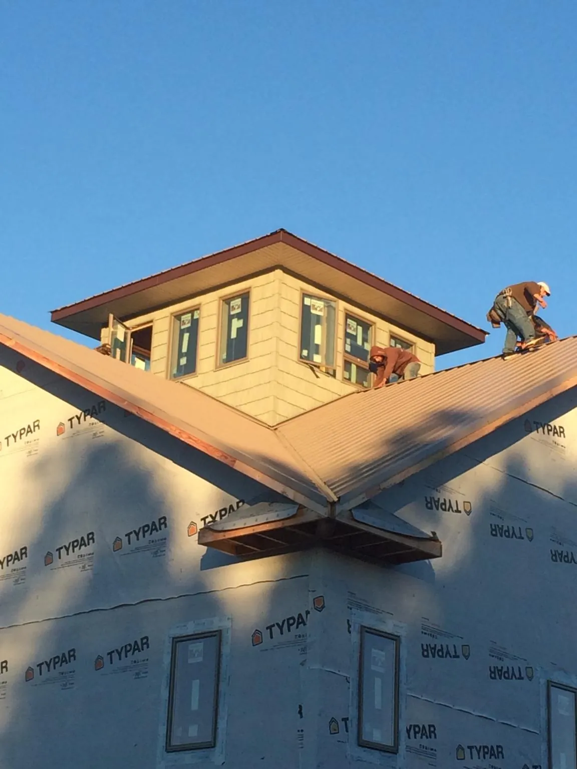 Roofers working around a rooftop cupola on a new metal roof at sunset — Roof Waterproofing in Sand Creek by Roofing Brothers